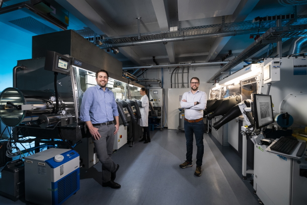 Junior Prof. Ulrich Paetzold (l.) and Ph. D. Tobias Abzieher (r.) in front of the new equipment for coating solar modules from the liquid phase (l.) and under vacuum (r.).