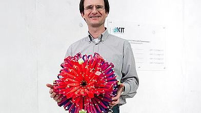 Professor Dr. Manfred Wilhelm mit dem Modell einer Superabsorberkugel, wie sie in Windeln verwendet wird.