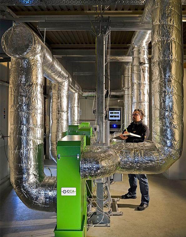 Langzeitbetrieb von Serienmodellen am Carola- Teststand, der mit Abgas aus einem 100 Kilowatt Hackgutkessel der HDG-Bavaria betrieben wird