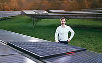 Dr. Ruben Hünig steht vor Solarmodulen.