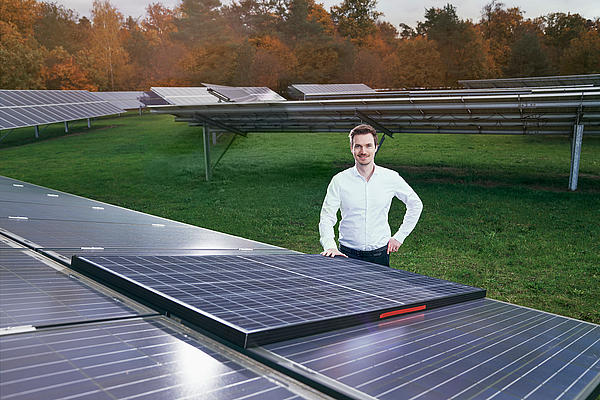 Dr. Ruben Hünig steht vor Solarmodulen.