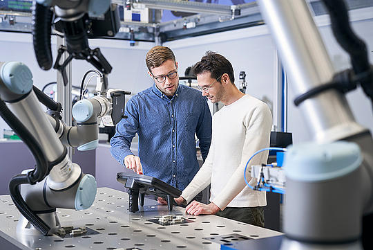 Two Agiprobot team members stand in the demonstrator factory.